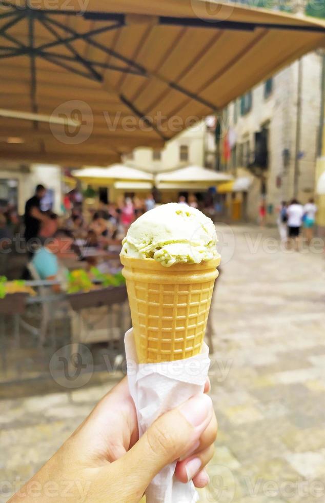 ice cream in a cone waffle cup in a hand on the background of the European old city photo