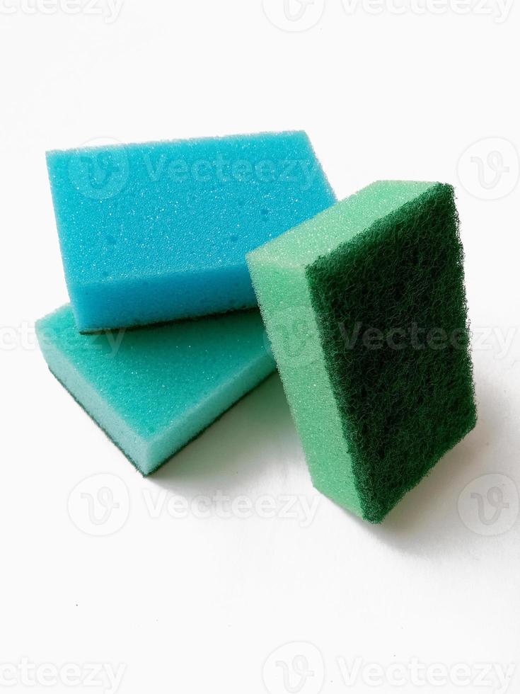 esponjas de cocina de lavado multicolores con estropajo verde abrasivo sobre fondo blanco foto