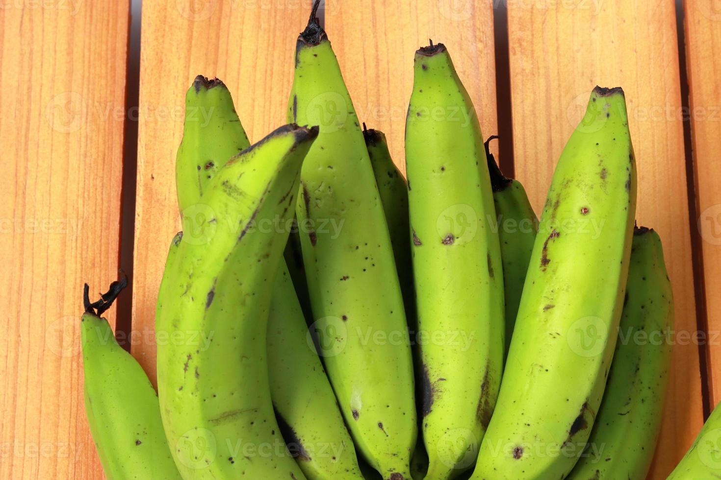 Banana on wooden background. Healthful red banana collection. Ripe bunch of banana photo