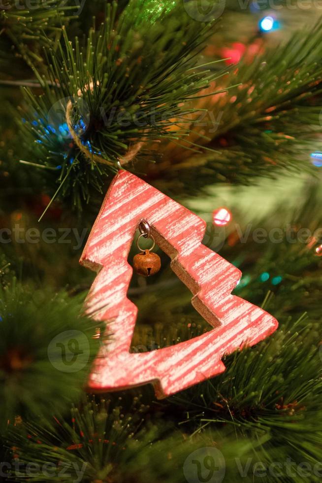 adornos navideños de madera roja en un abeto con luces navideñas borrosas. foto