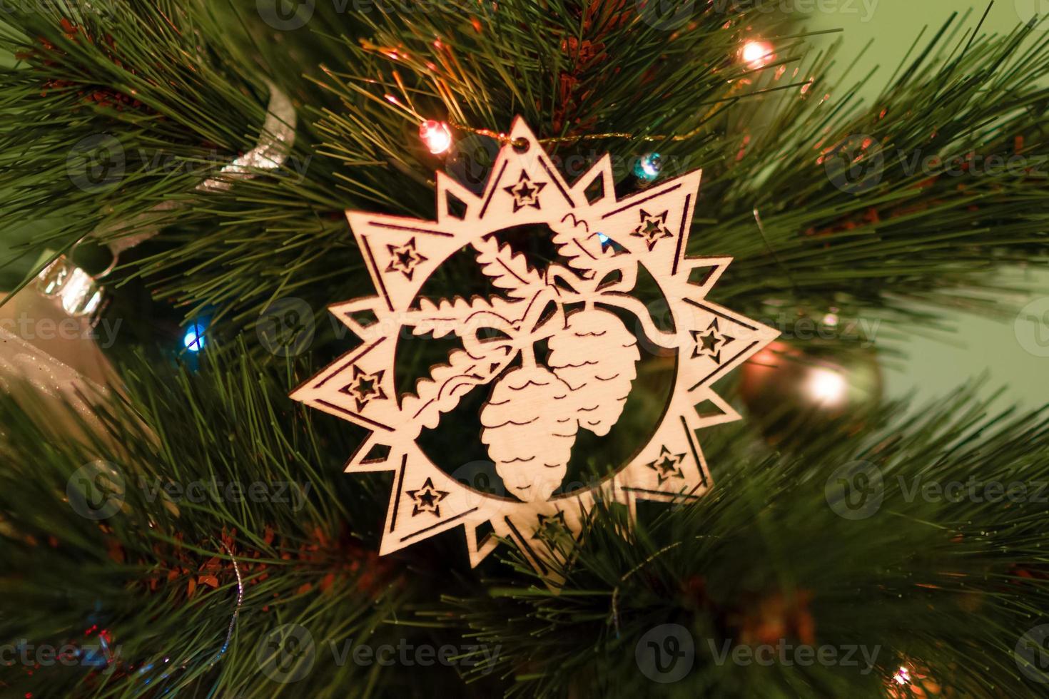 Wooden Christmas decorations on a fir tree with blurred Christmas lights. photo