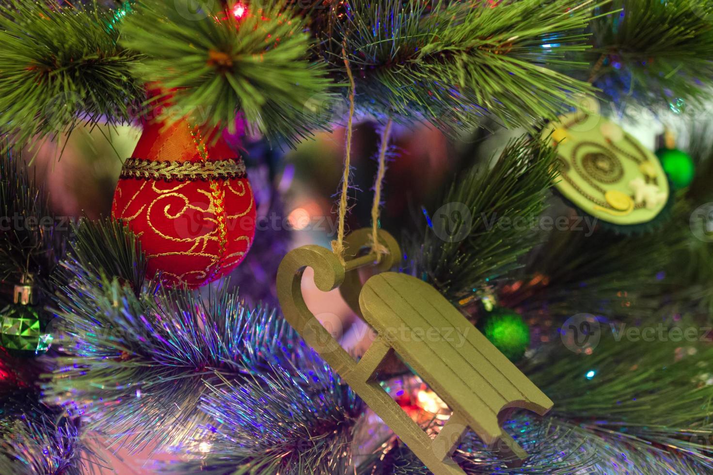 coloridas decoraciones navideñas en un abeto con luces borrosas. foto