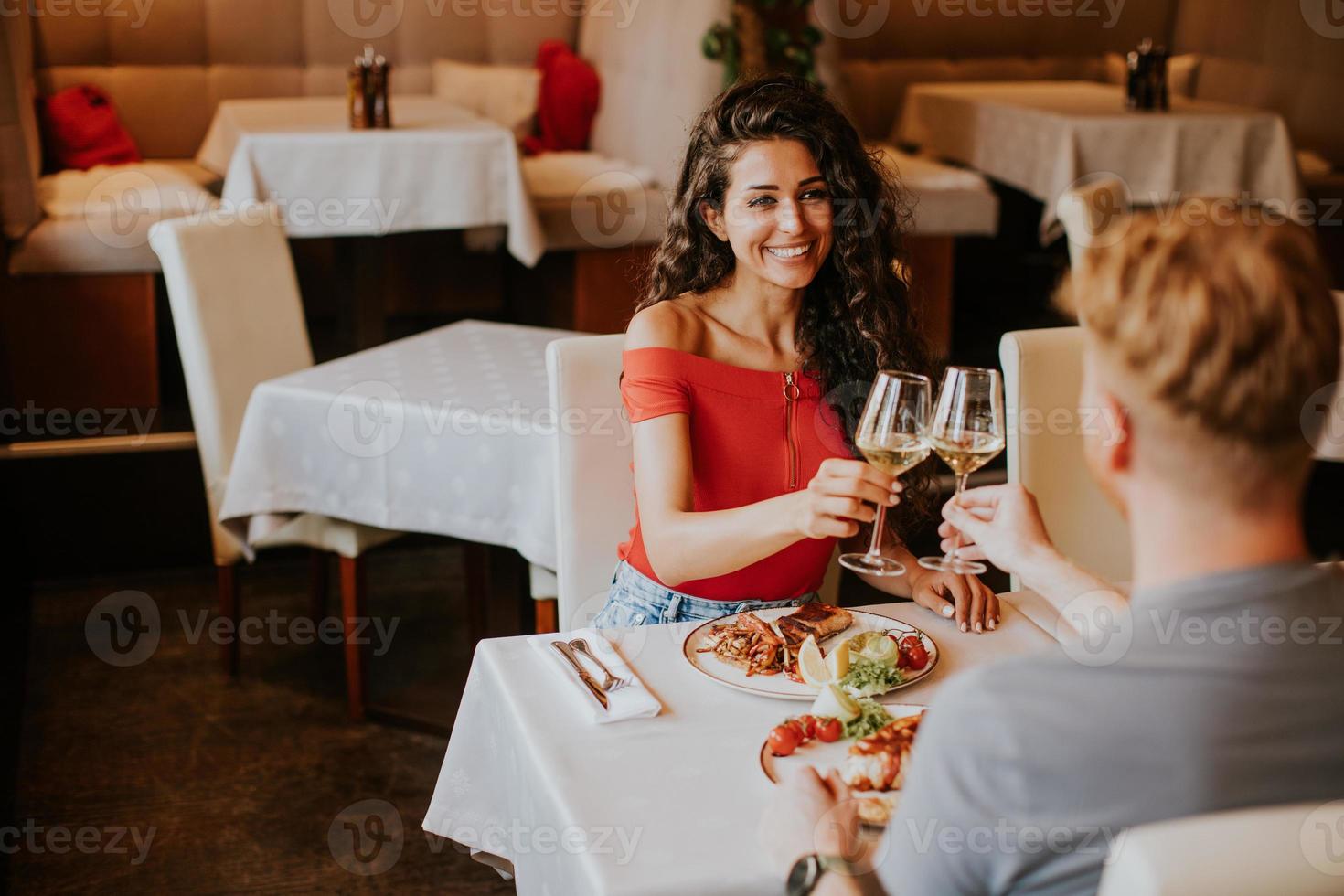 pareja joven almorzando con vino blanco en el restaurante foto