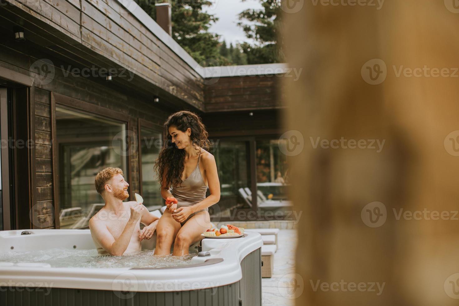 Young couple enjoying in outdoor hot tub on vacation photo