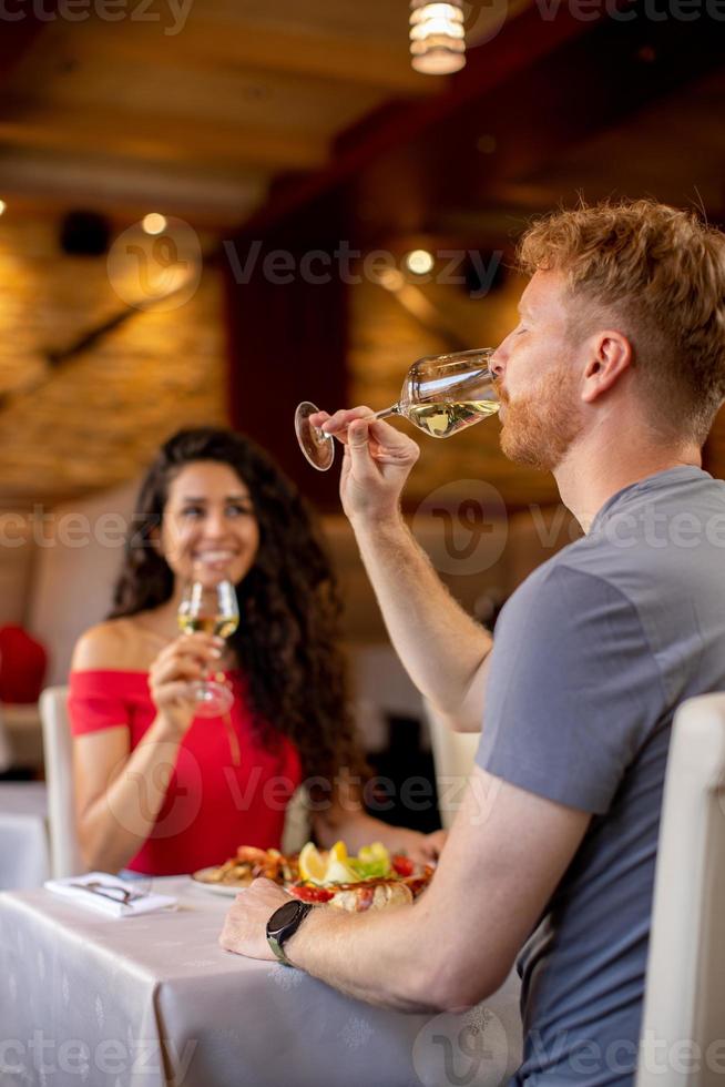 pareja joven almorzando con vino blanco en el restaurante foto