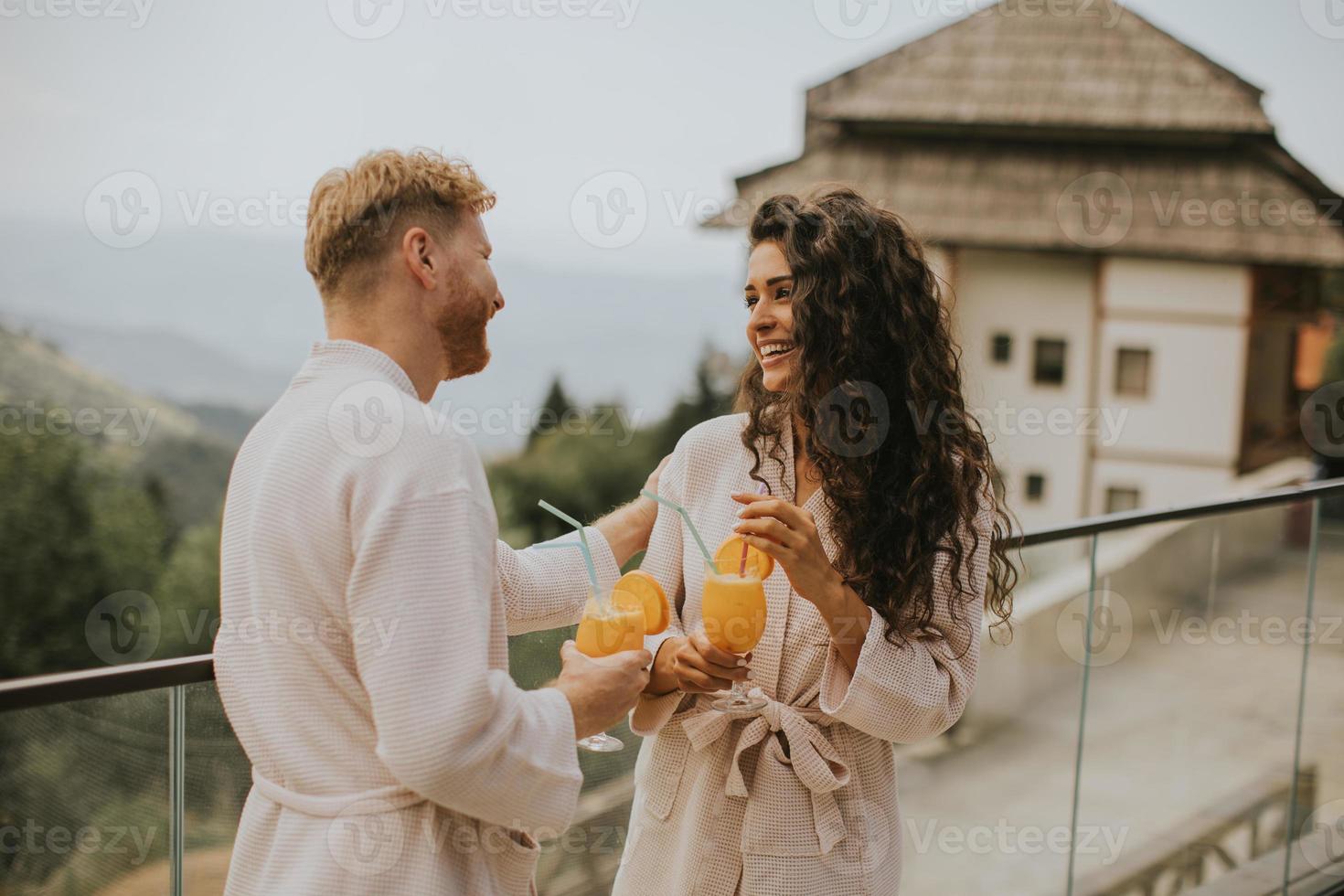 pareja joven relajándose en la terraza al aire libre y bebiendo jugo de naranja fresco foto