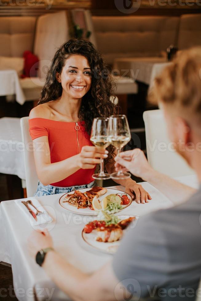 pareja joven almorzando con vino blanco en el restaurante foto