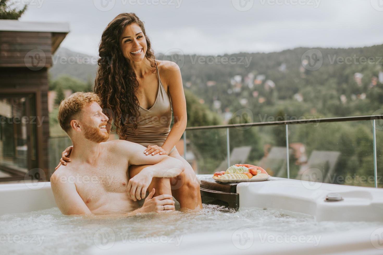 Young couple enjoying in outdoor hot tub on vacation photo