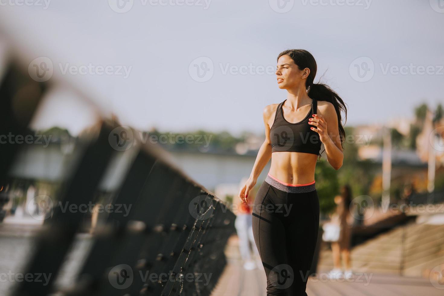 Active young beautiful woman running on the promenade along the riverside photo