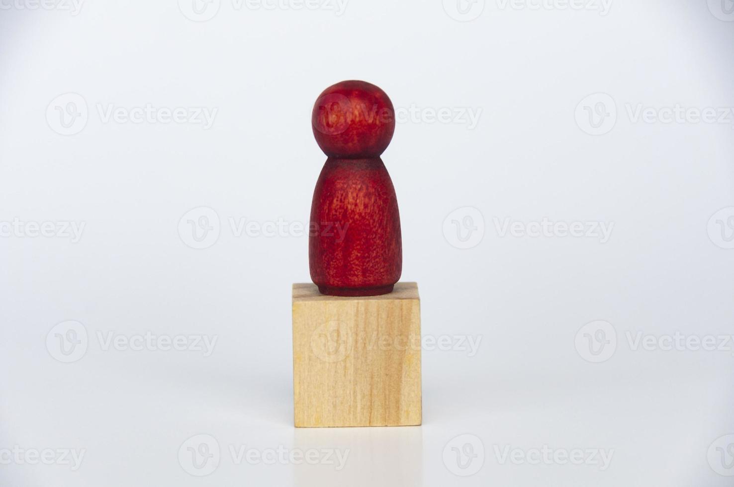 Wooden red people figure on top of wooden cube. Lonely concept photo