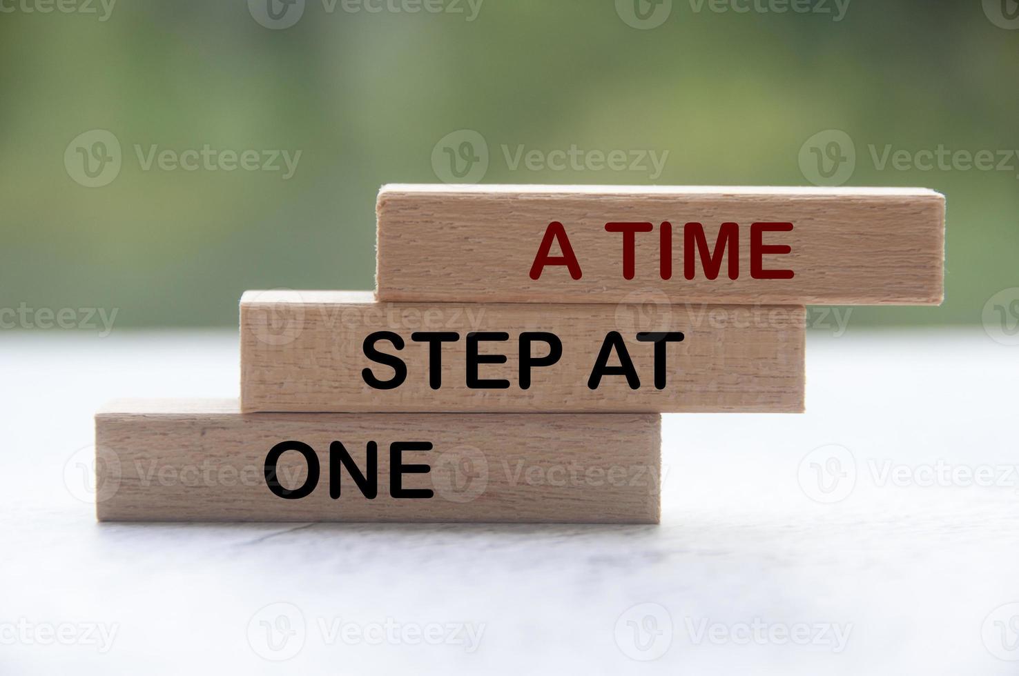 One step at a time words on wooden blocks with blurred nature background. Work completion concept. photo