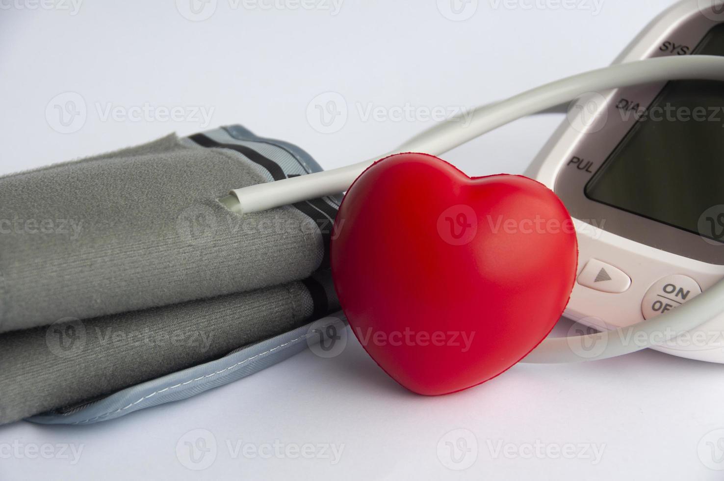 Digital blood pressure monitor and heart shape on white background photo