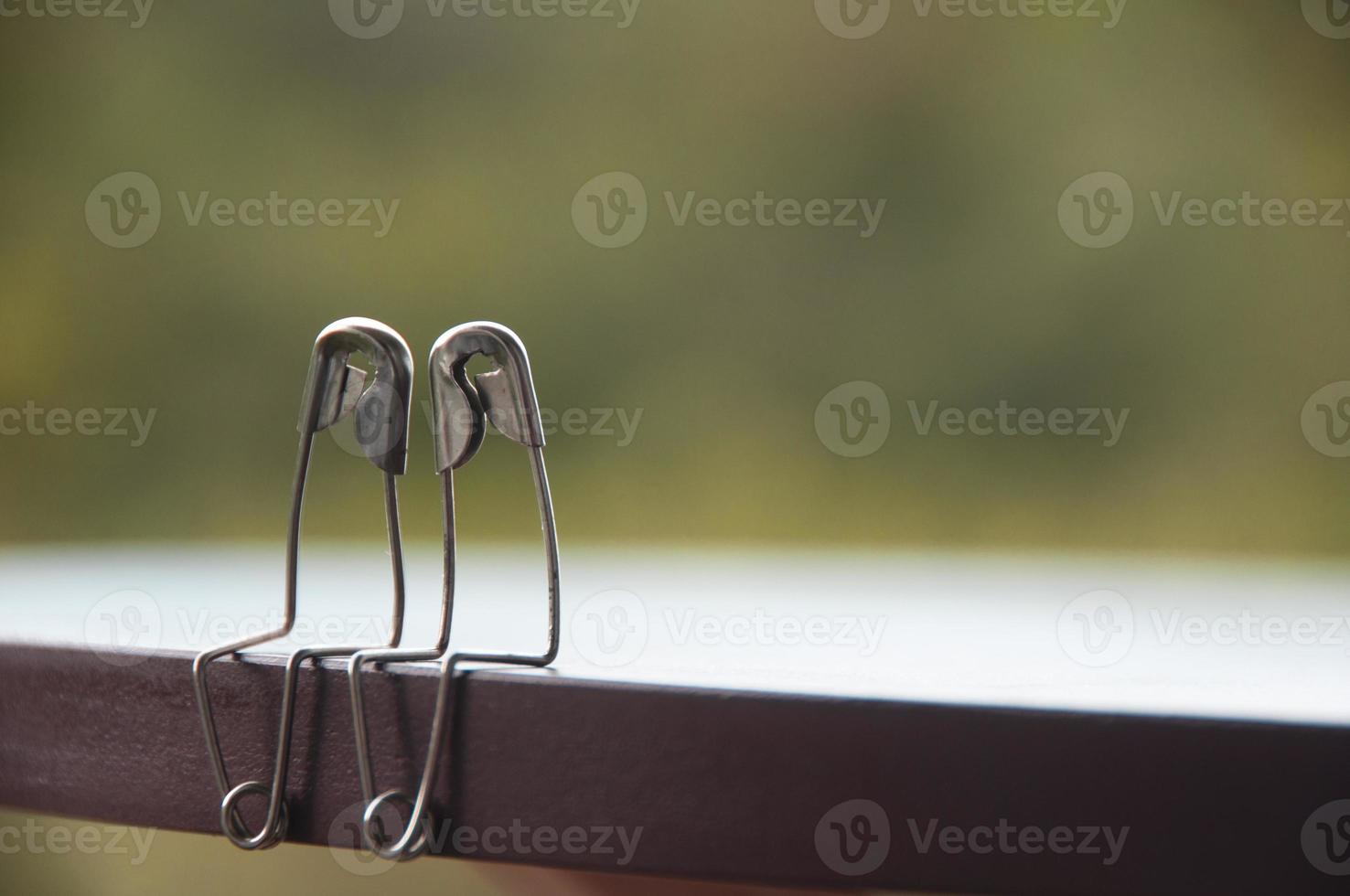Safety pin couple sitting on table with customizable space for text and ideas. Love and romance concept photo
