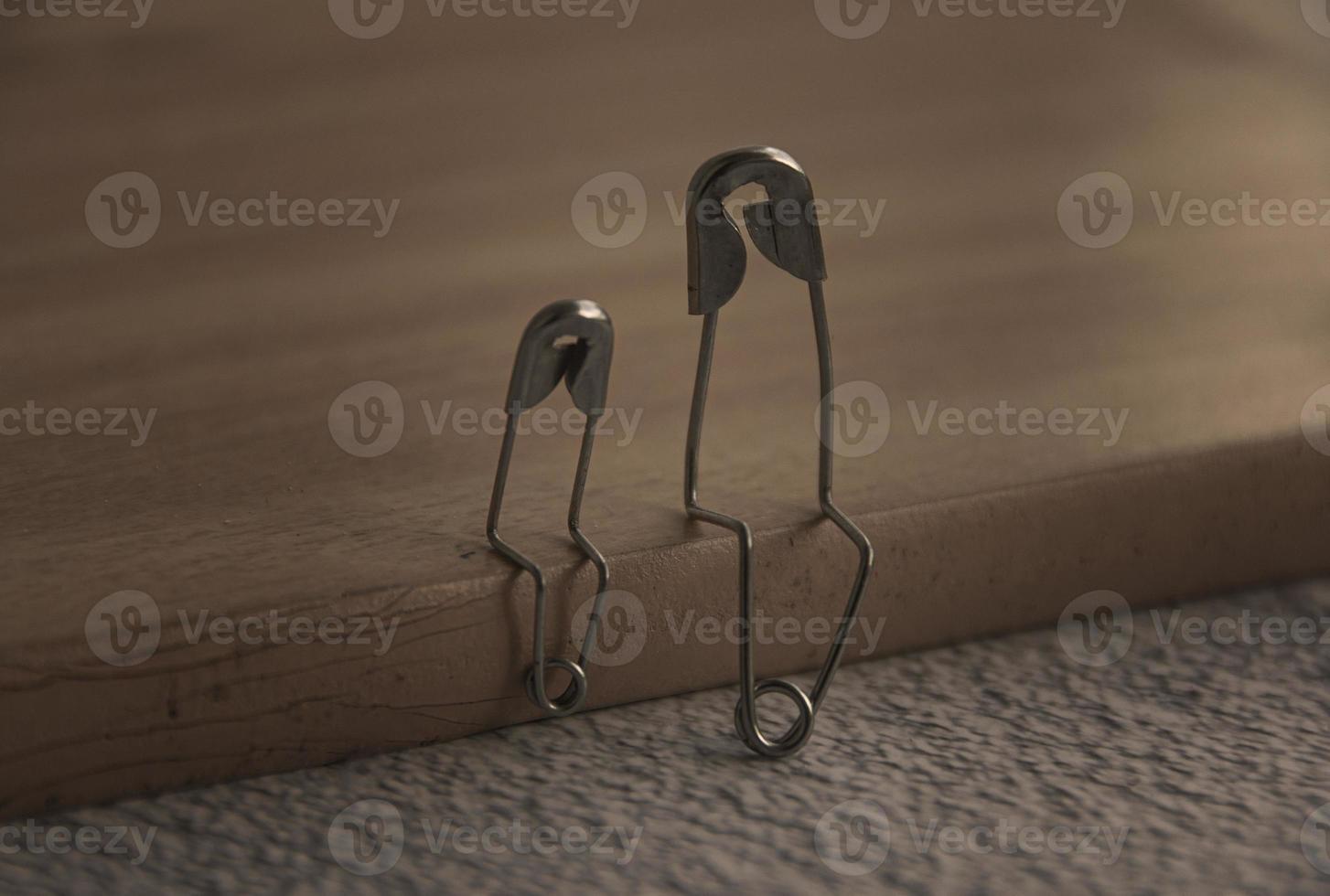 Model safety pin of parent and child sitting on wooden cover with customizable space for text or ideas. Family concept photo