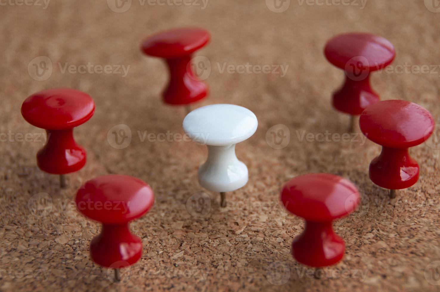 White push pin surrounded by red push pins. Harassment and discrimination concept photo