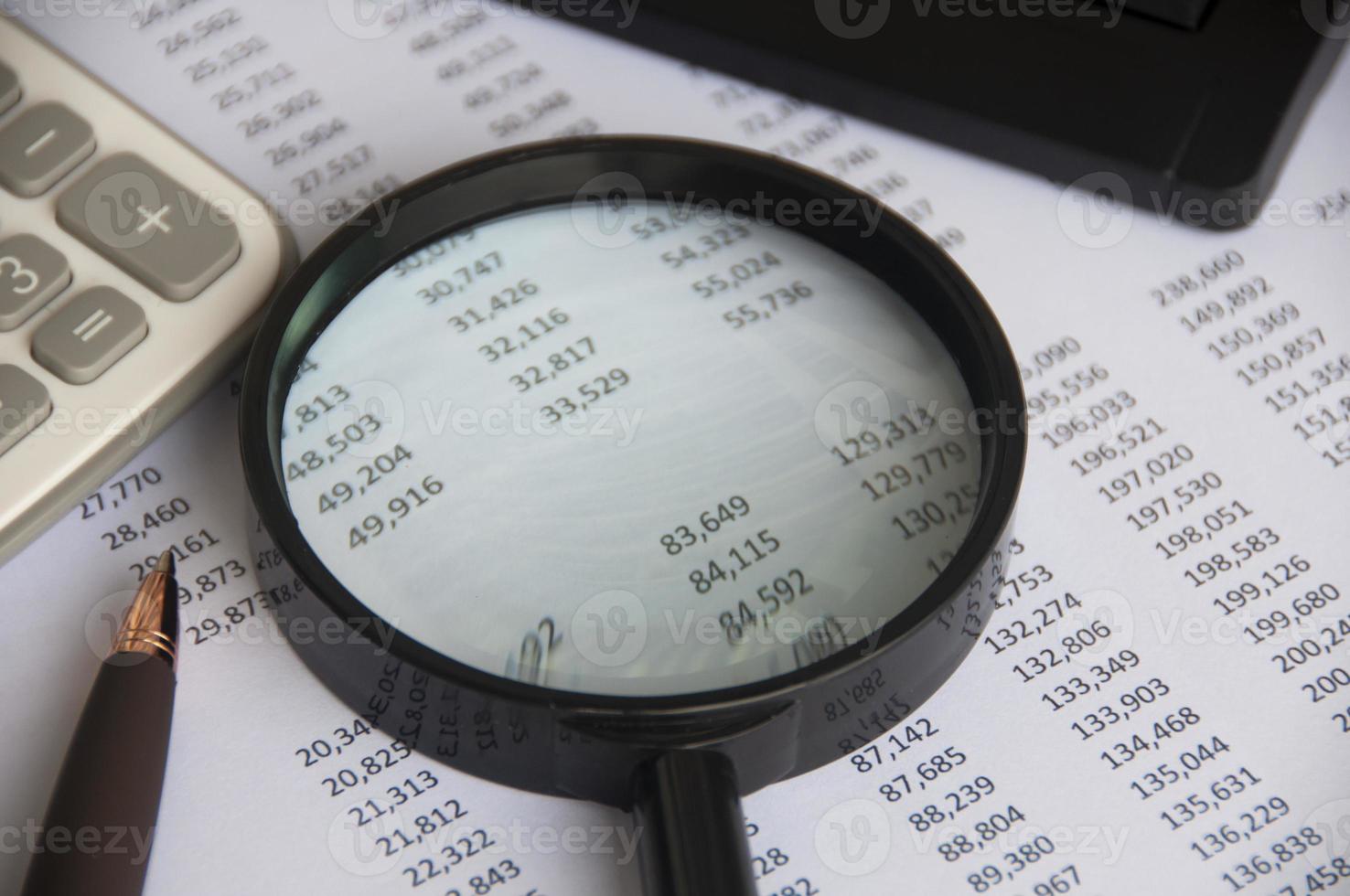 Business analysis concept - magnifying glass with calculator and number analysis background. Copy space photo