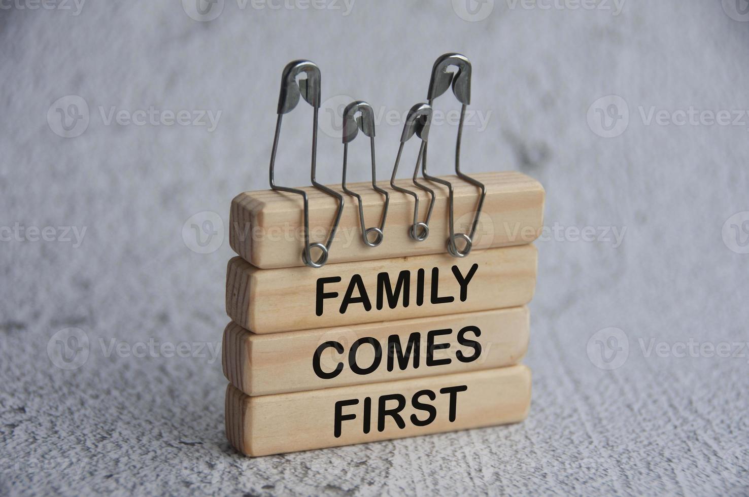 Model safety pin of family sitting on wooden blocks with text - Family comes first. Family concept photo