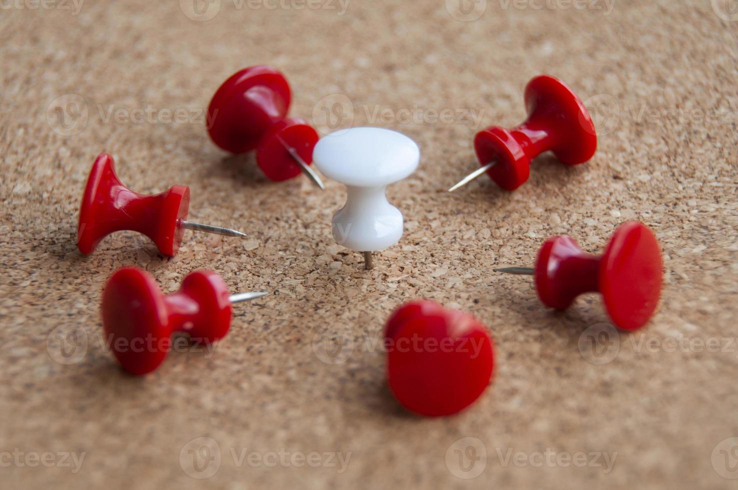 Red push pins targeting on white push pin. Harassment and discrimination concept. photo