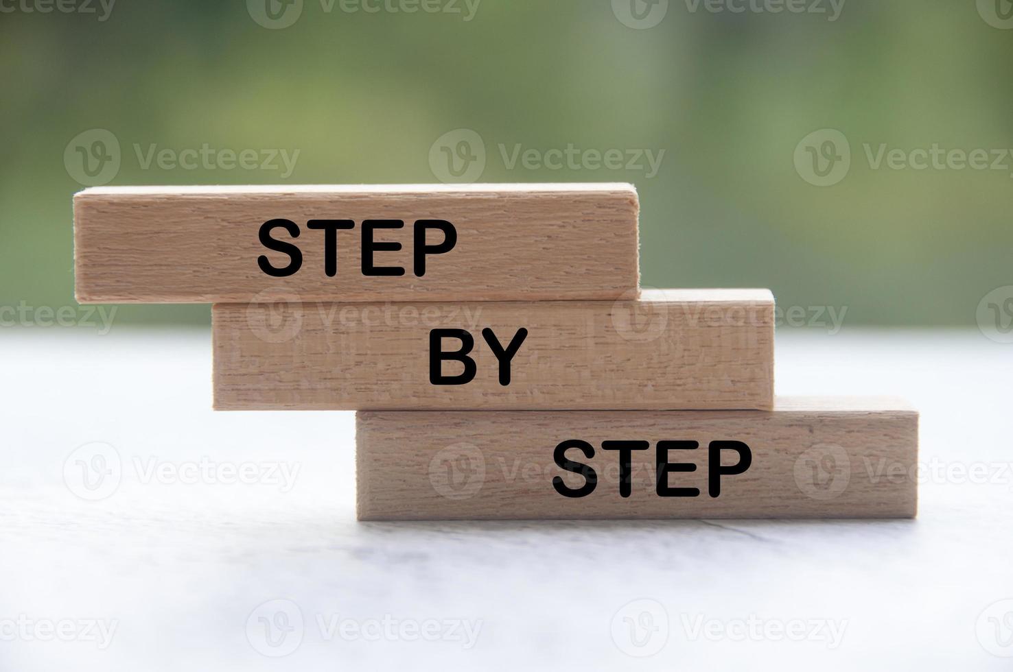 Step by step text on wooden blocks with blurred nature background. photo