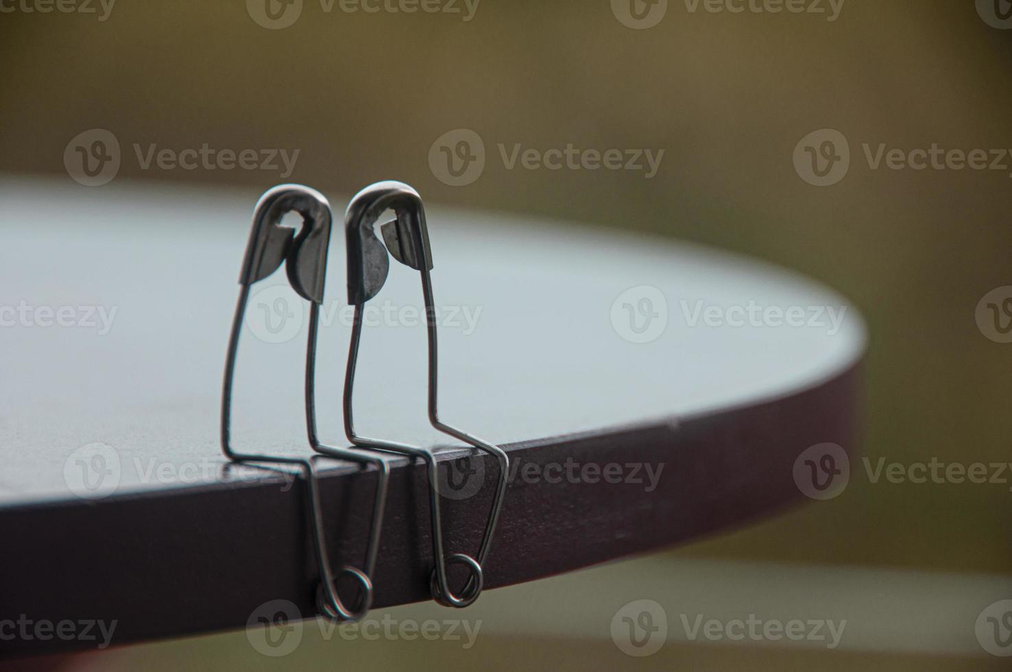 Safety pin couple sitting on table with customizable space for text and ideas. Love and romance concept photo