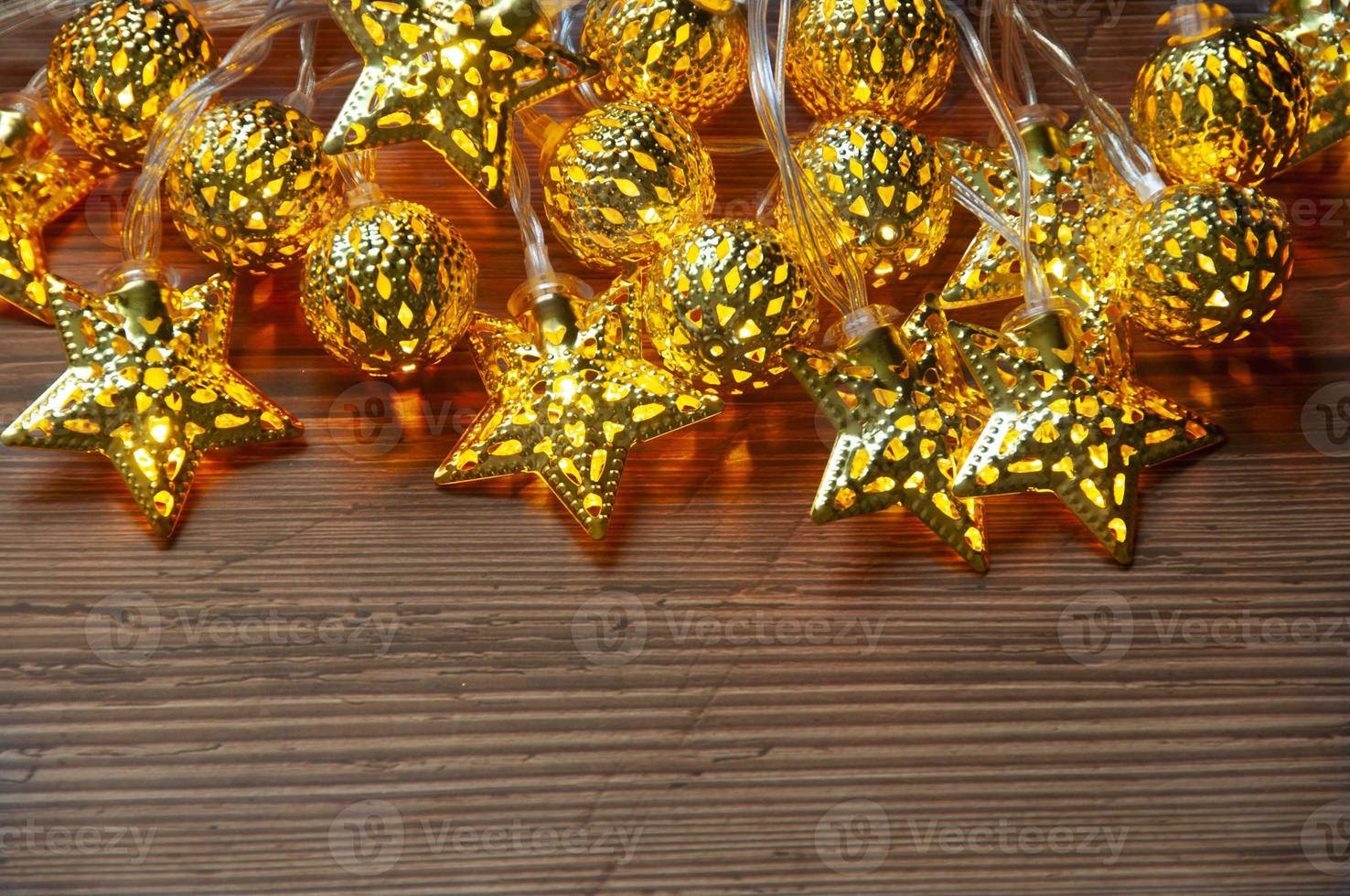Shining Christmas golden ball and stars on wooden background with customizable space for text. Copy space photo