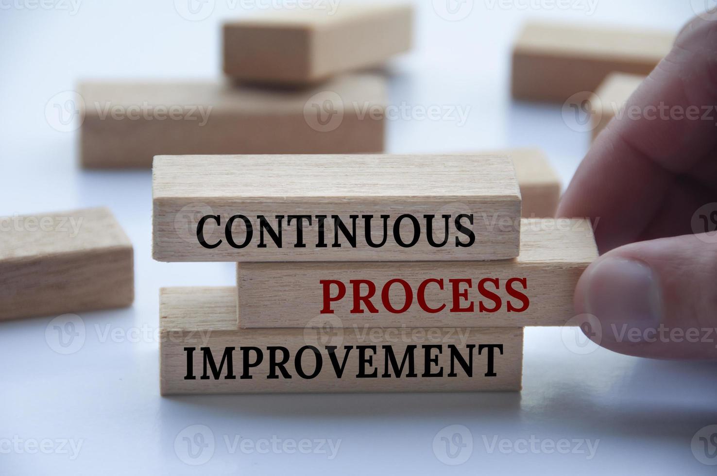 Hand holding wooden blocks with continuous process improvement text on wooden blocks on white background. Process improvement and business concept. photo