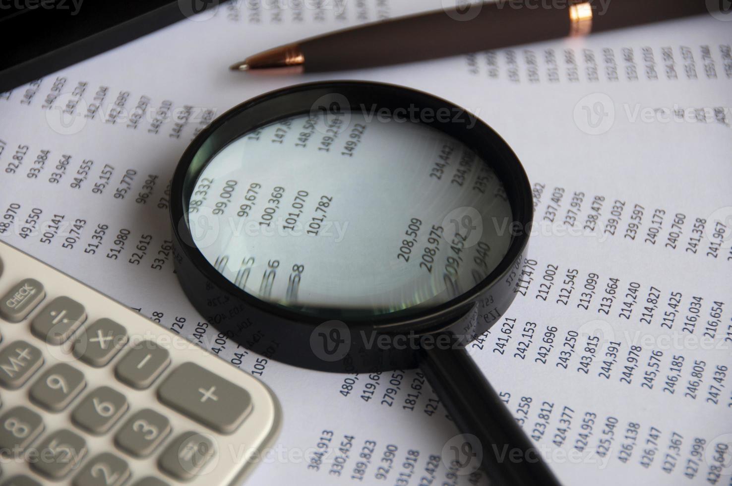 Business analysis concept - magnifying glass with pen, calculator and number analysis photo