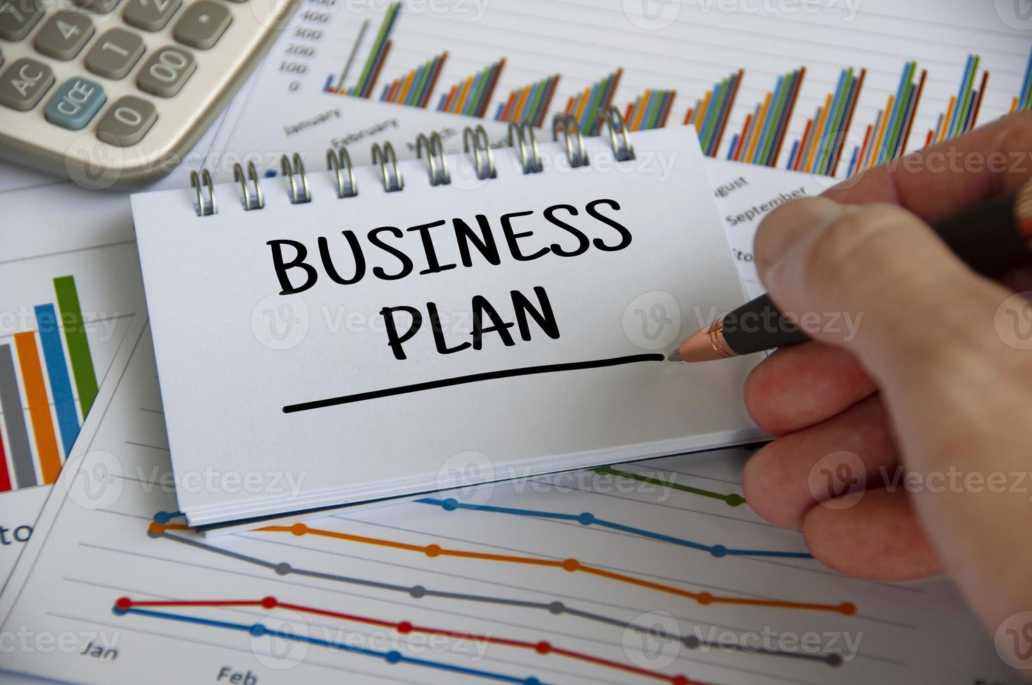 Business plan written on notepad with graph analysis background. Business plan concept photo