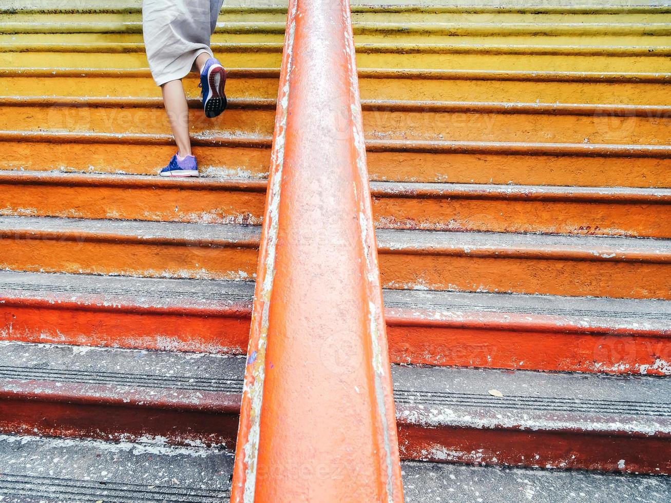 A lady walking up a vibrant steps in a temple photo