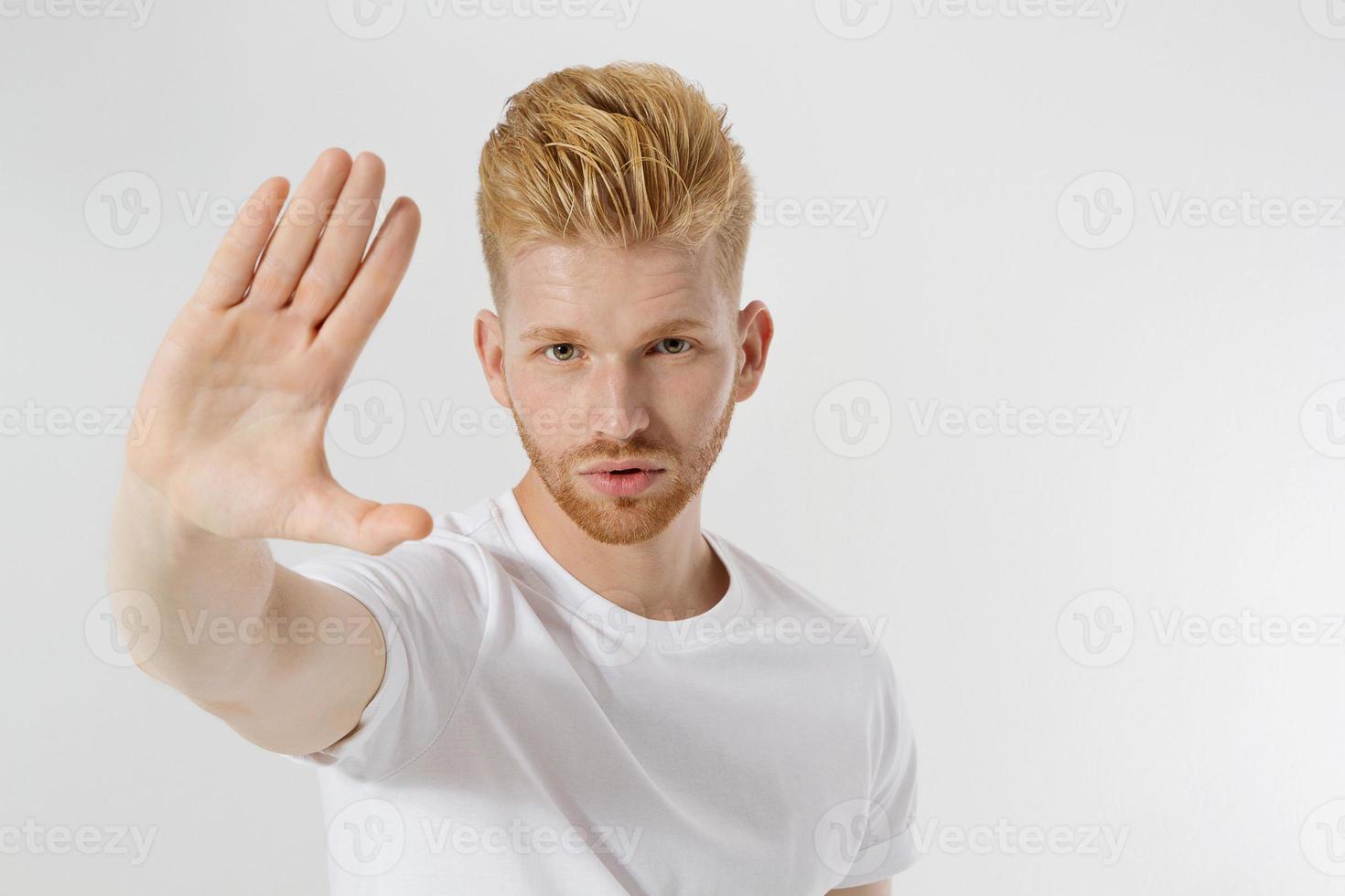 Stop hands sign. Young man in blank template white t shirt showing stop gesture. Redheaded and red beard guy isolated. hazard protection concept. Copy space and mock up on t-shirt. Selective focus photo