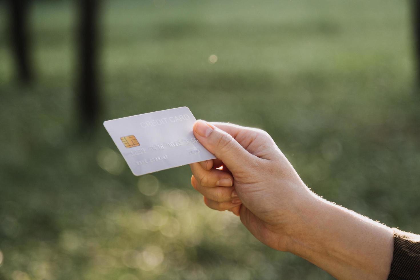 manos sosteniendo la tarjeta de crédito y usando la computadora portátil. las compras en línea foto