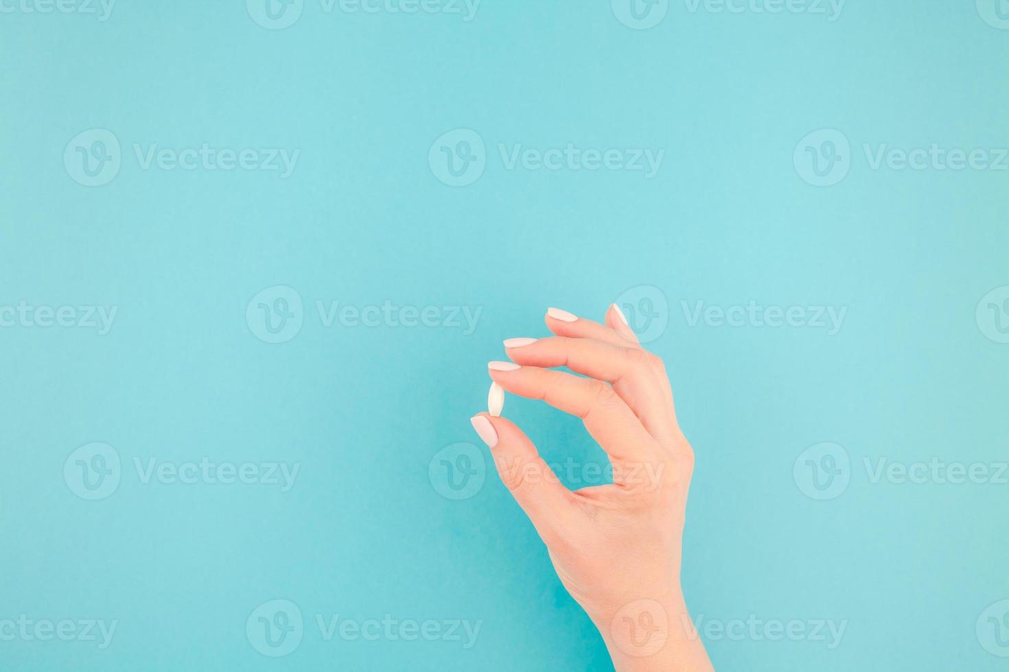 Female hand holding a white pill photo