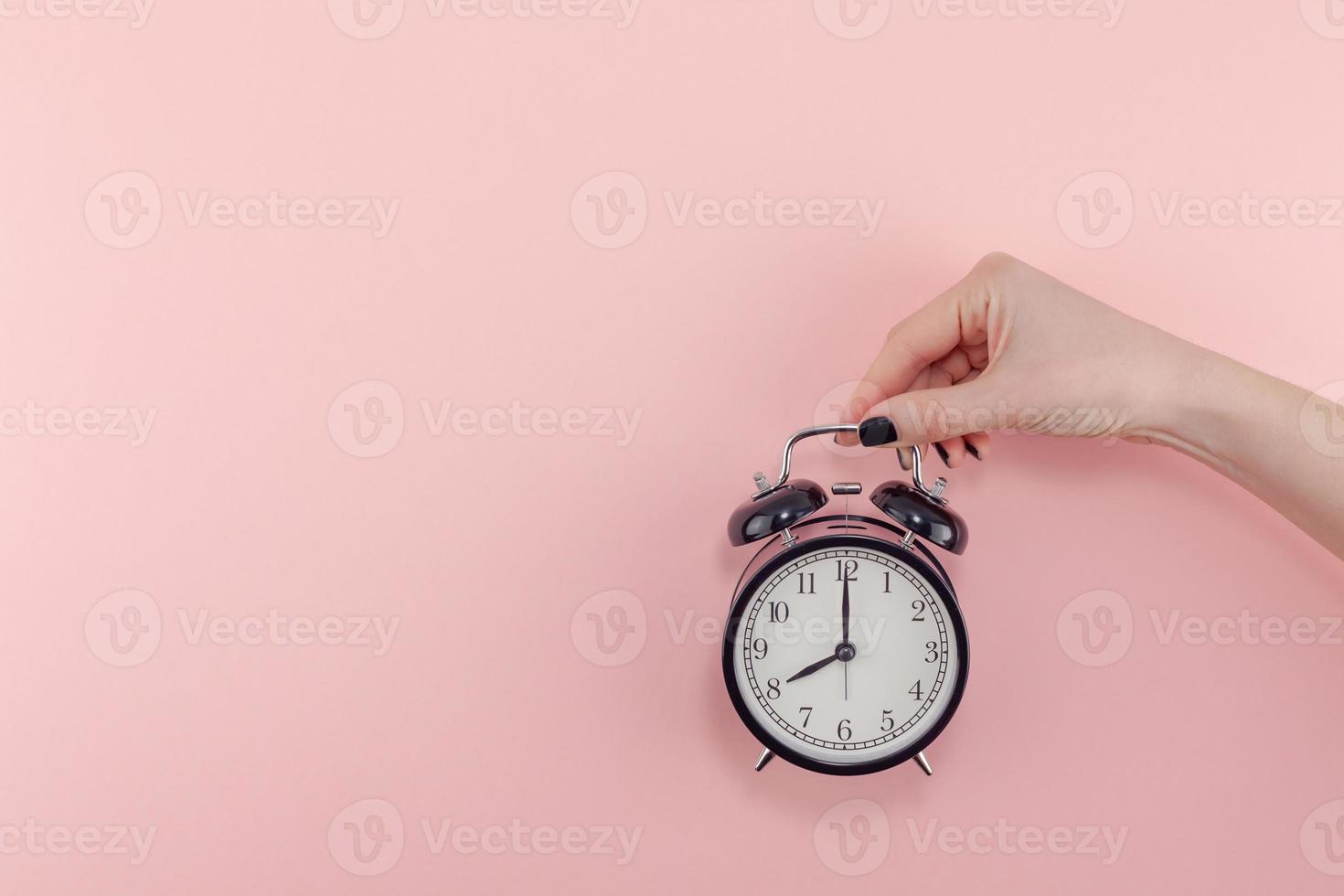 Female hand with alarm clock. Morning concept photo