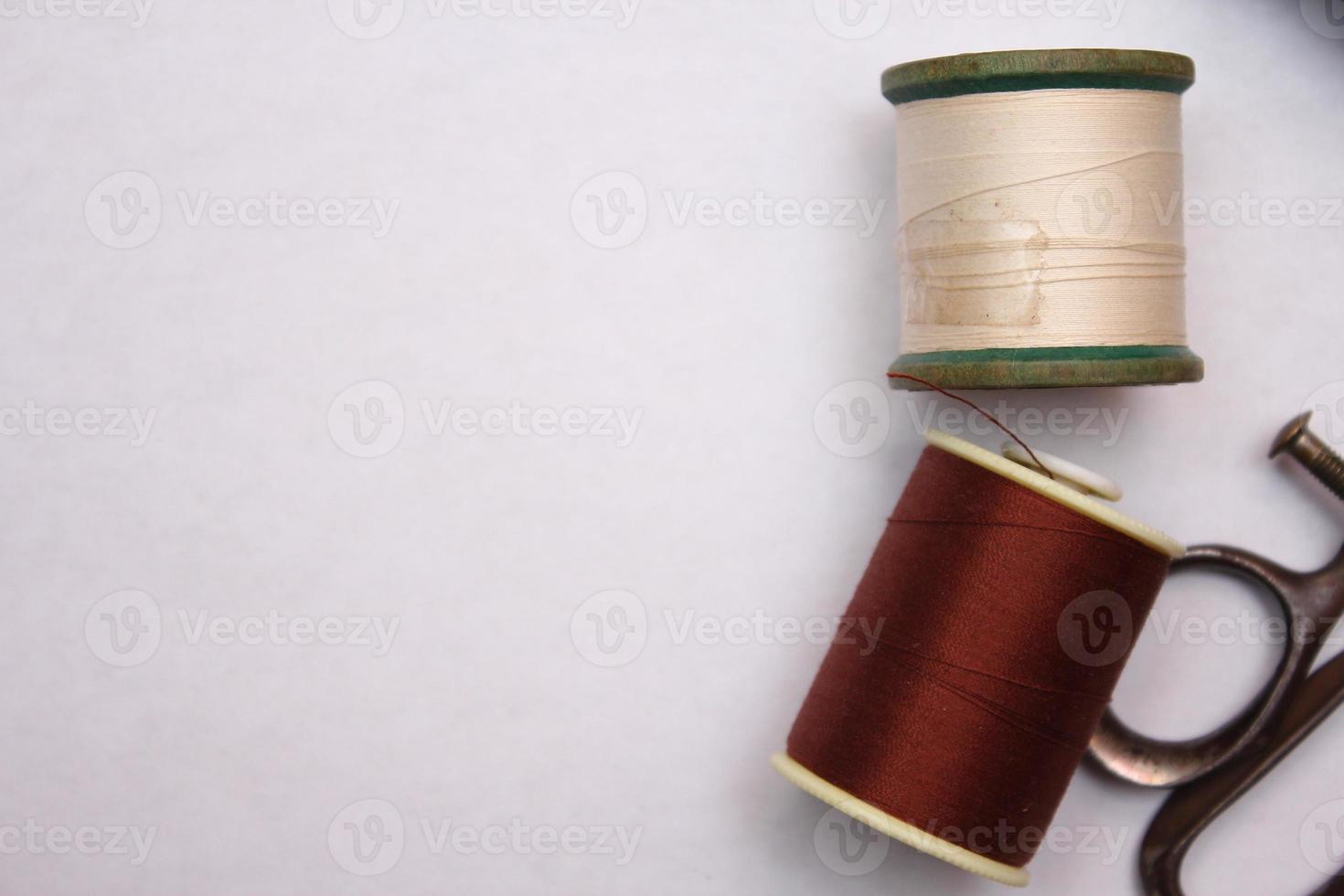 Multi-colored threads and old scissors spread out on a white floor, retro scissors, flat lay, copy space. photo