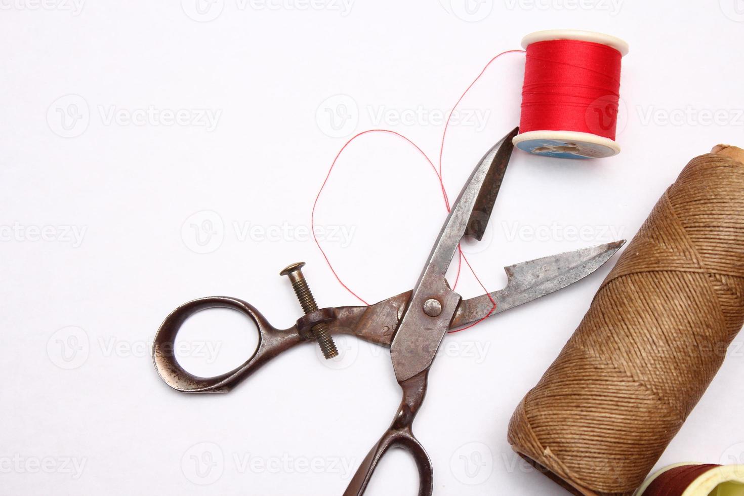 Multi-colored threads and old scissors spread out on a white floor, retro scissors, flat lay, copy space. photo