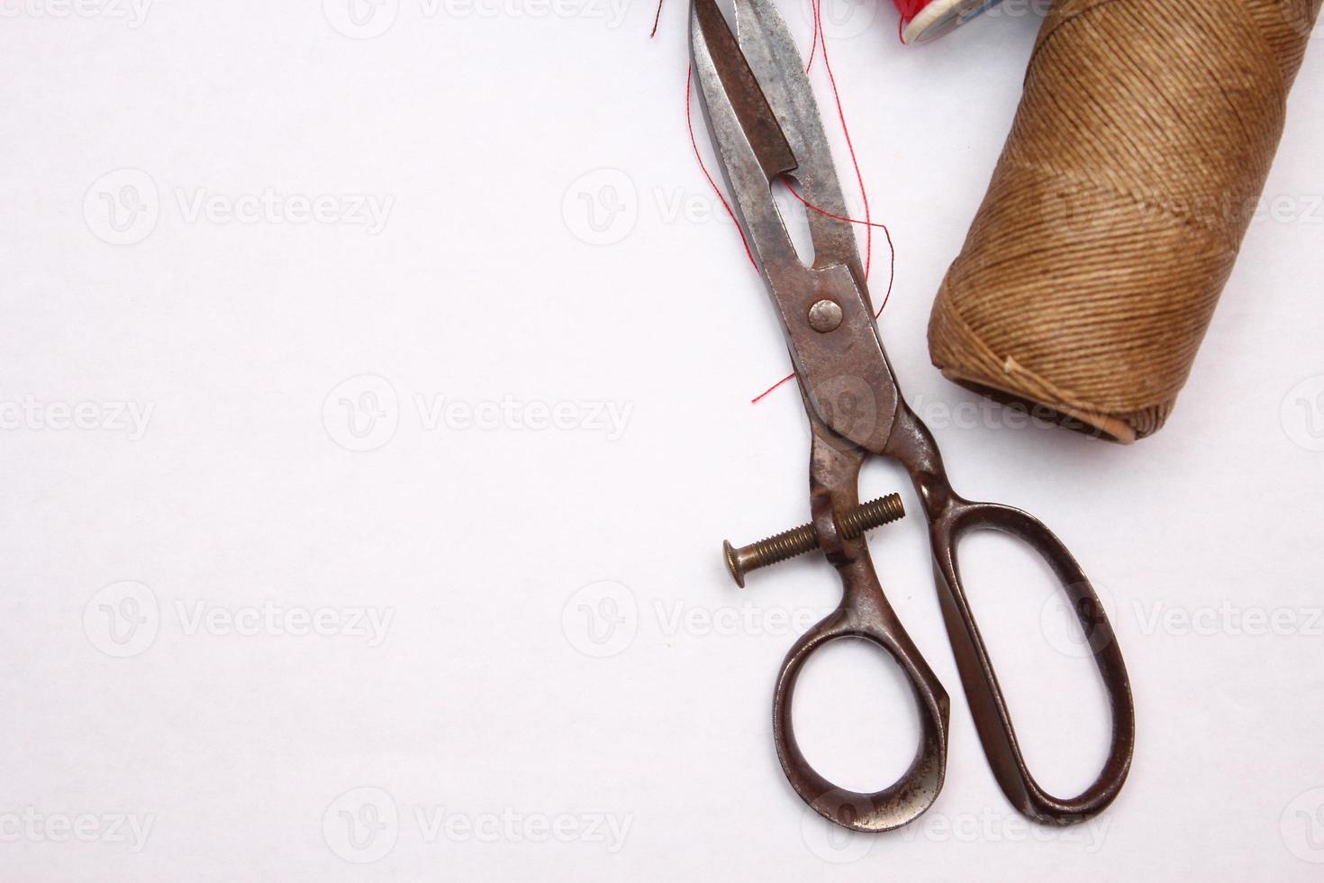 Multi-colored threads and old scissors spread out on a white floor, retro scissors, flat lay, copy space. photo