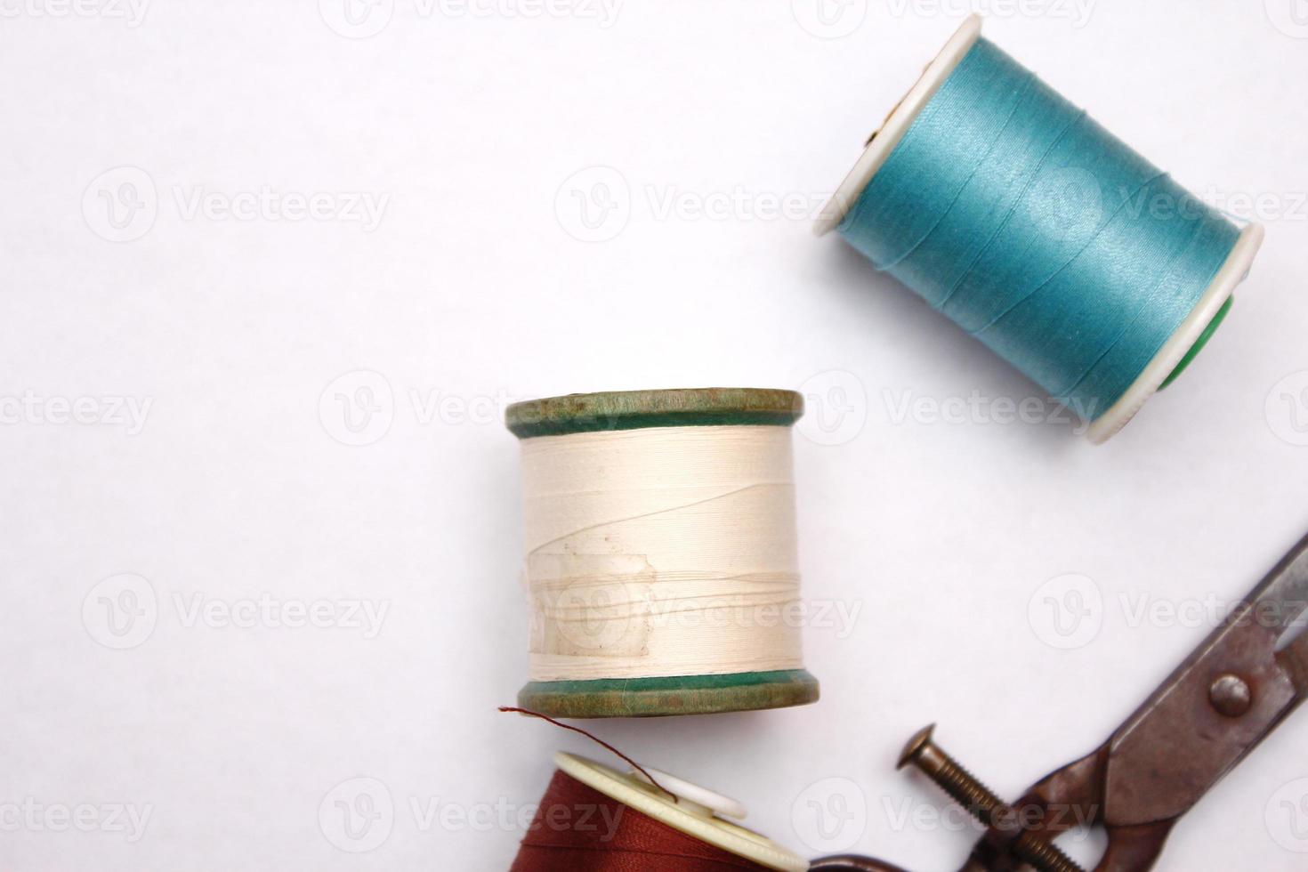 Multi-colored threads and old scissors spread out on a white floor, retro scissors, flat lay, copy space. photo