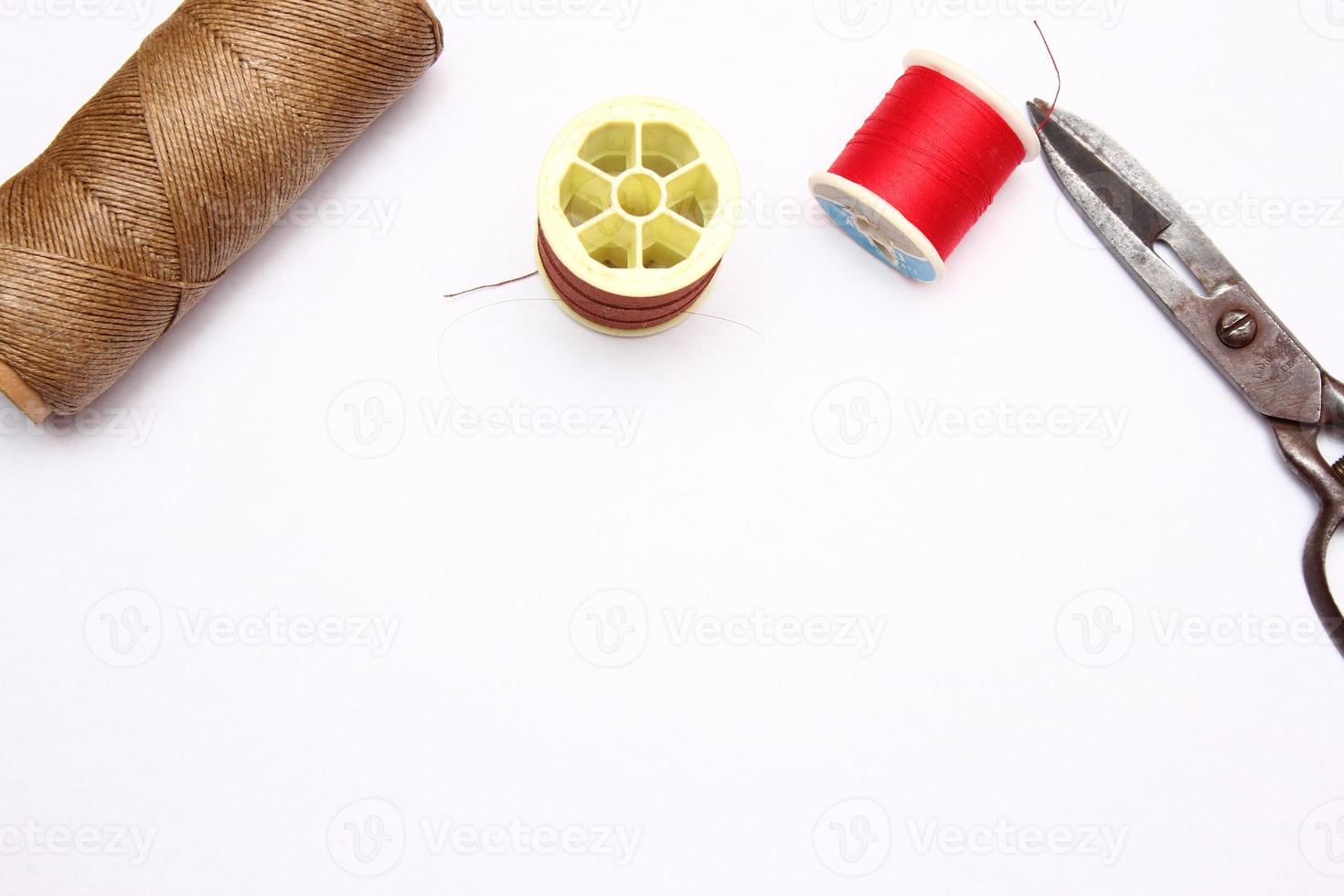 Multi-colored threads and old scissors spread out on a white floor, retro scissors, flat lay, copy space. photo