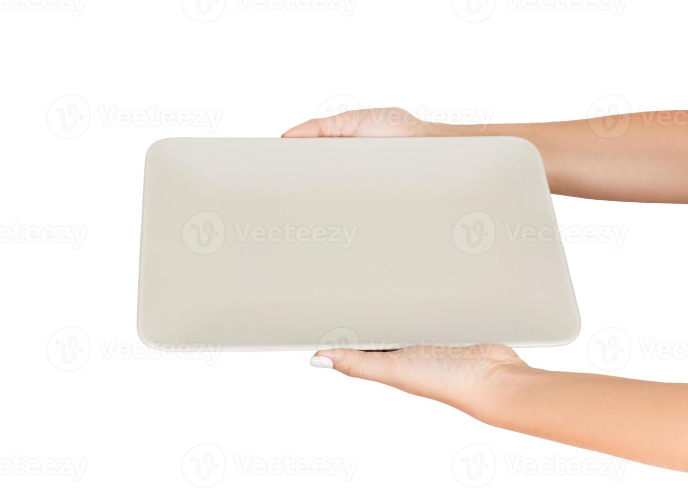 Blank white matte rectangular plate in female hand. perspective view, isolated on white background photo