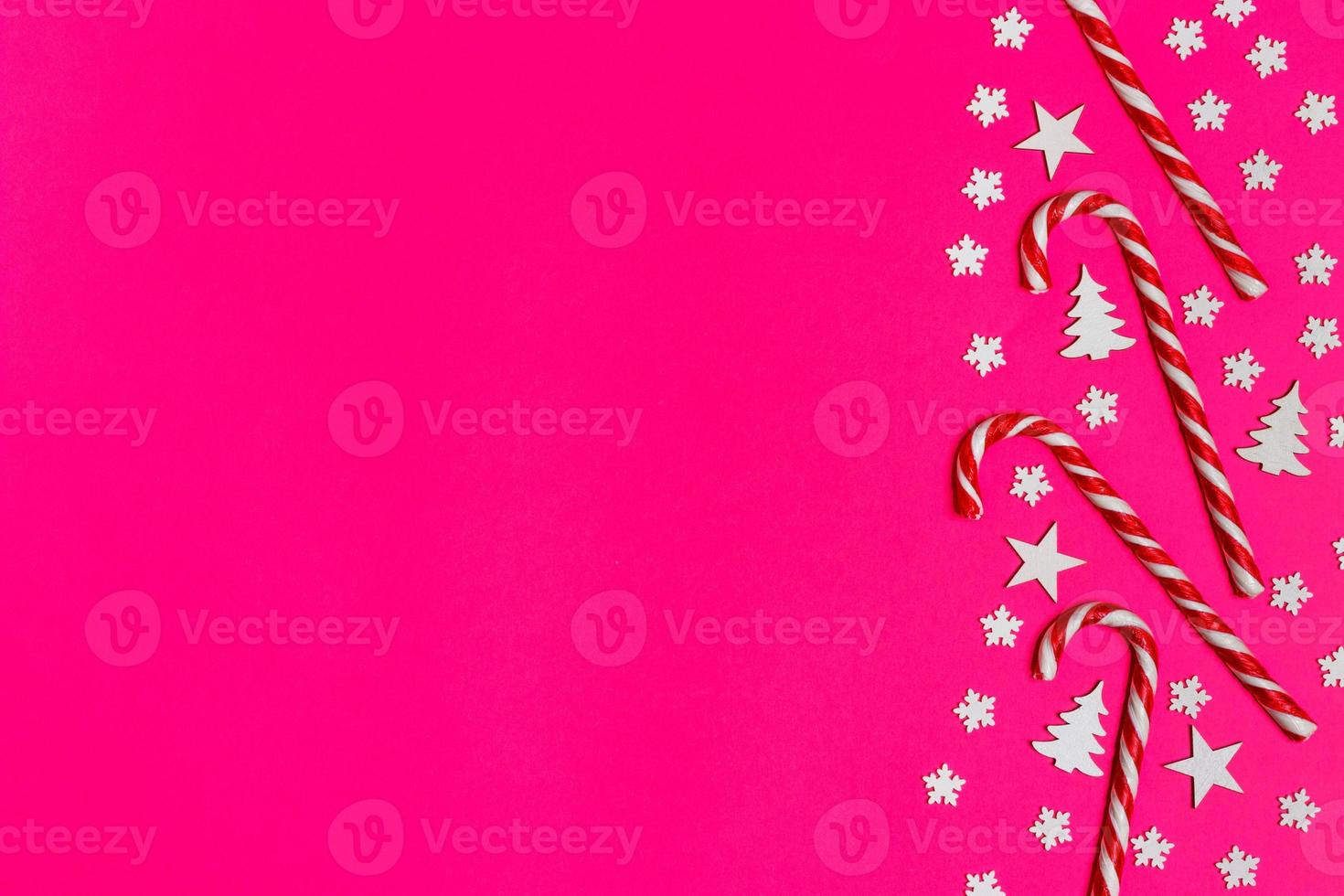 Christmas candy cane lied evenly in row on pink background with decorative snowflake and star. Flat lay and top view photo