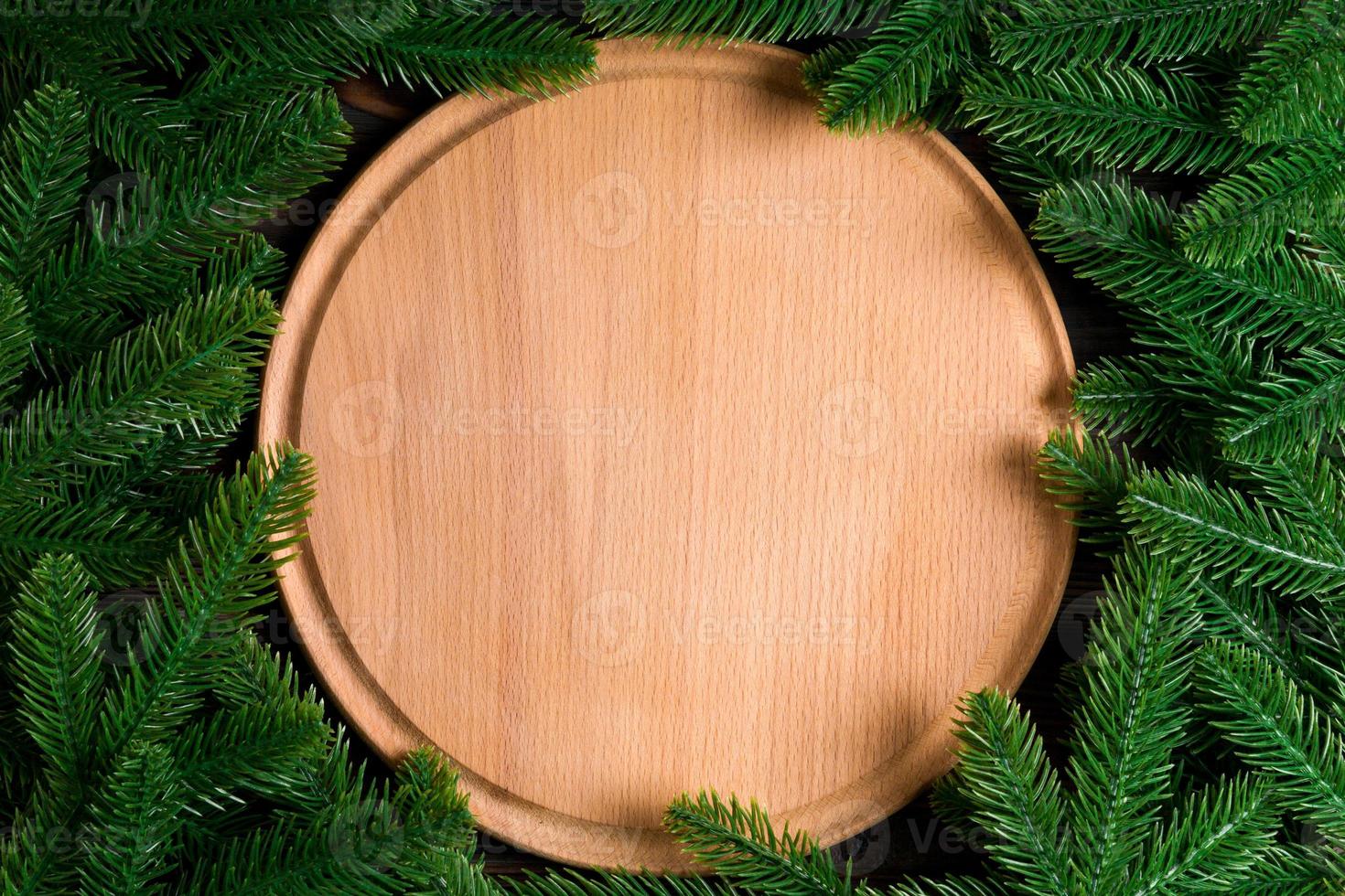 Top view of wooden plate decorated with fir tree branches. New Year dinner concept with empty space for your design photo