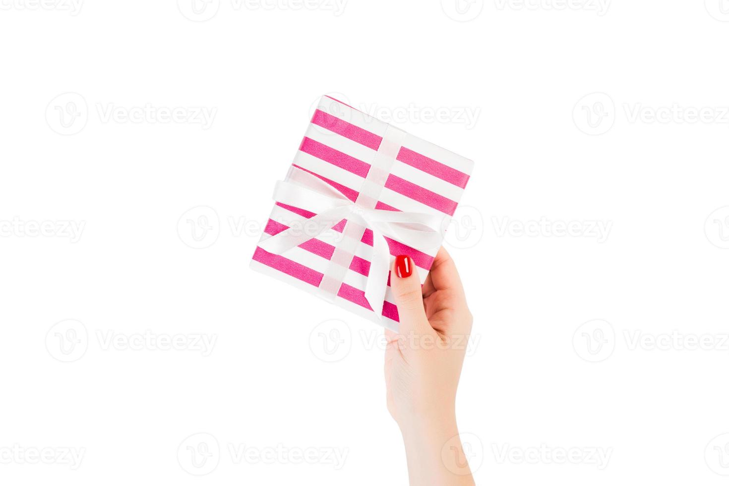 Woman hands give wrapped Christmas or other holiday handmade present in pink paper with white ribbon. Isolated on white background, top view. thanksgiving Gift box concept photo