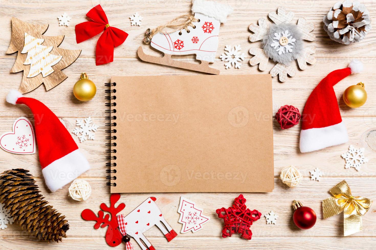 Top view of notebook on wooden background made of Christmas decorations. New Year concept photo
