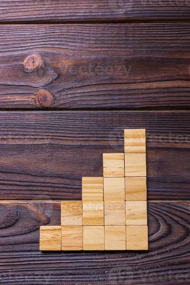 A wooden blocks cube over black wooden textured background with copy space for add word text title. Concept or conceptual Wood block stair or five steps. Cubic photo