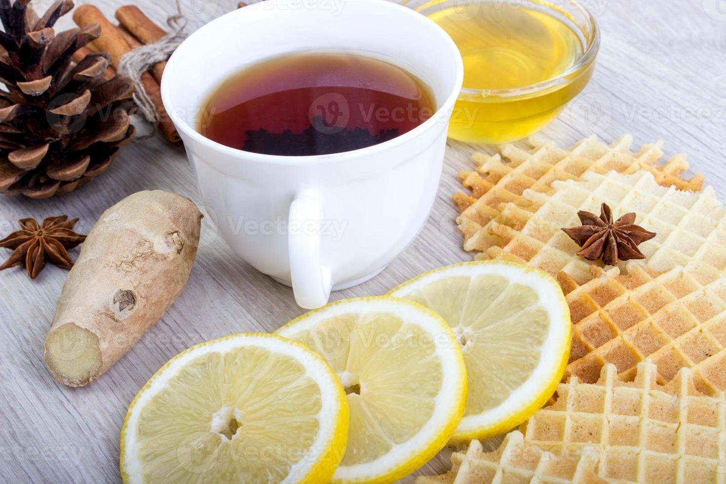 Cup of tea with honey, pinecone, badian, ginger, waffles and cinnamon photo