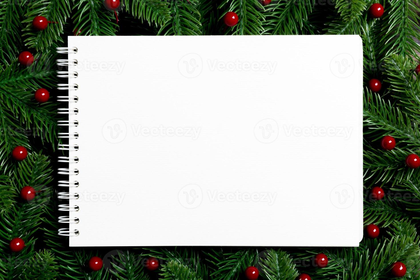 Top view of notebook decorated with a frame made of fir tree on wooden background. New Year time concept photo