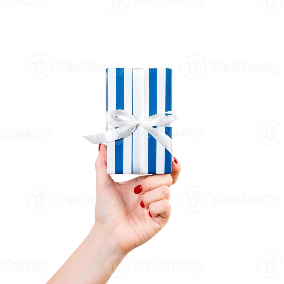 Woman hands give wrapped Christmas or other holiday handmade present in blue paper with white ribbon. Isolated on white background, top view. thanksgiving Gift box concept photo