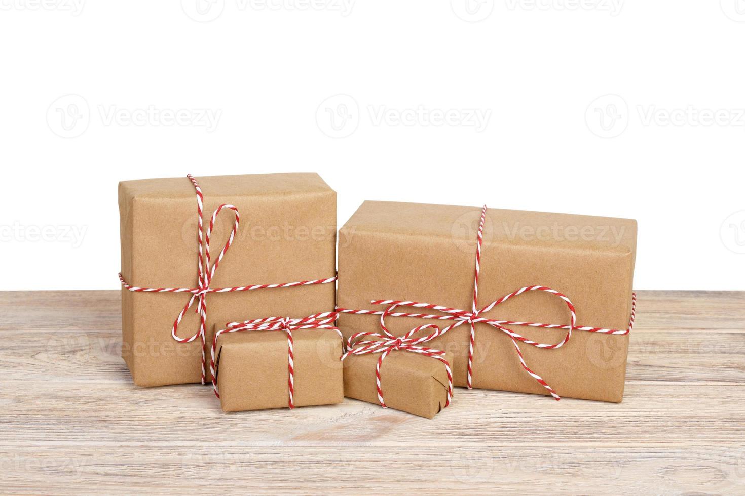 Gift box wrapped in recycled paper with ribbon bow on wooden table. Isolated photo