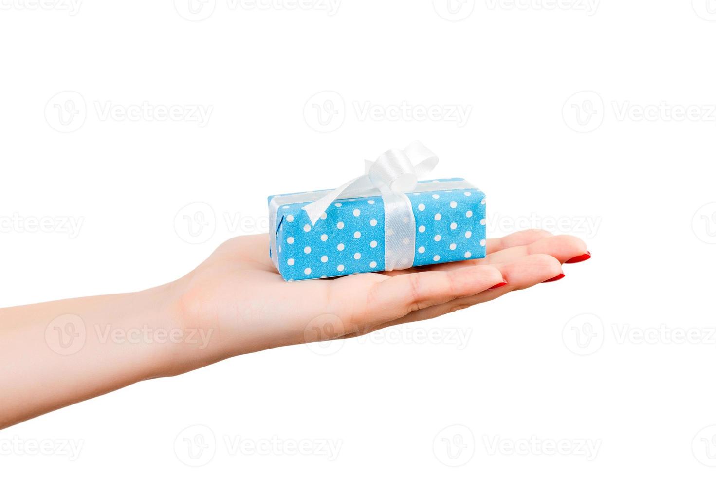 Woman hands give wrapped Christmas or other holiday handmade present in blue paper with white ribbon. Isolated on white background, top view. thanksgiving Gift box concept photo