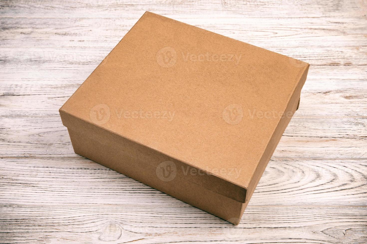 Brown closed cardboard box on a wooden background. top view vintage, toned, blank for you design photo